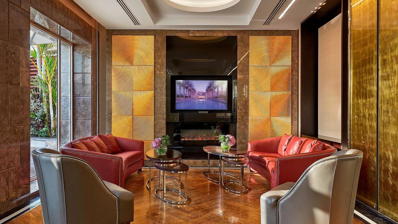 A lounge at JW Marriott Hotel Cairo, with red sofas and gold panels